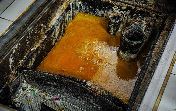 foul odors, slow drainage, and visible grease buildup are all signs that your grease trap may need cleaning